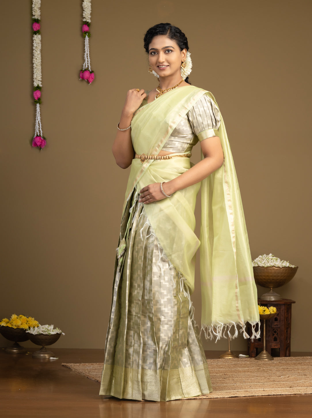 Woman wearing a light green saree with a brown background