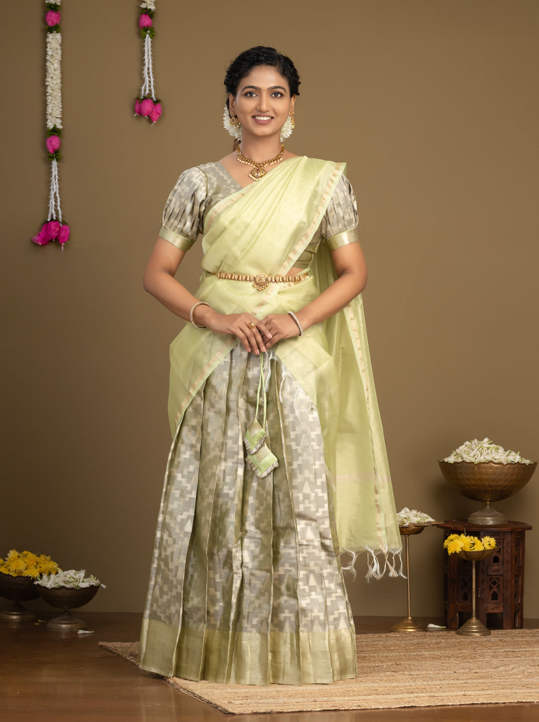 Woman in a light green saree with a neutral background
